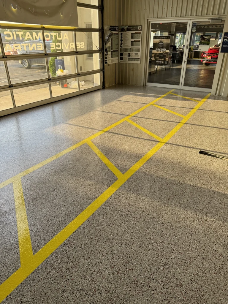 Polished concrete floor in auto service center with yellow lines marking parking spaces and walkways