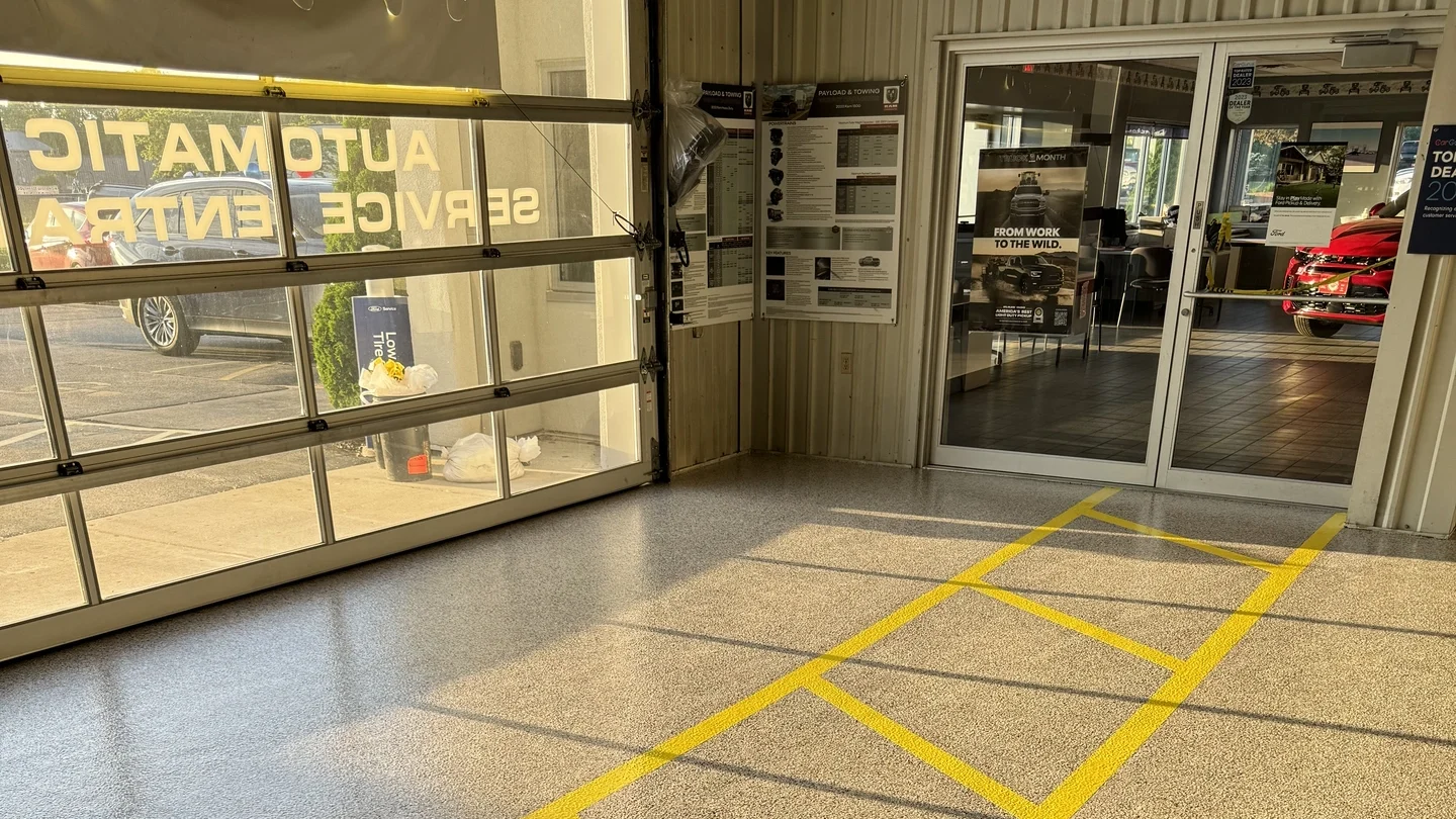 Polished concrete floor in auto service center with yellow lines marking parking spaces and walkways