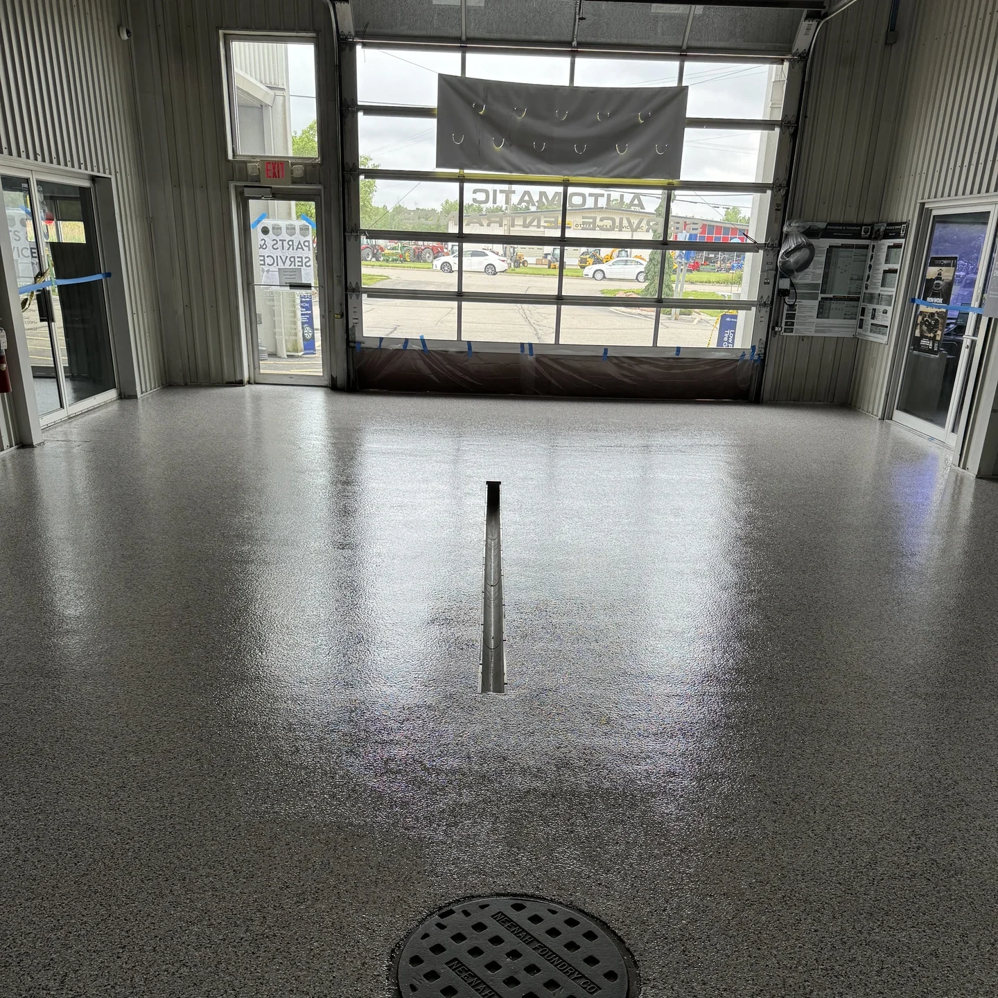 Metallic gray resinous floor coating with a decorative manhole cover drain in an automotive repair shop