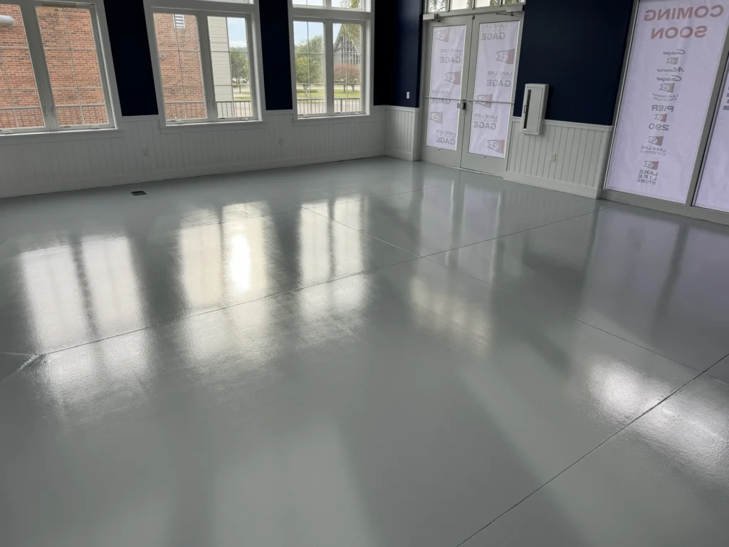 Smooth, reflective commercial floor coating in an empty room with large windows and doors, showing a high-gloss finish