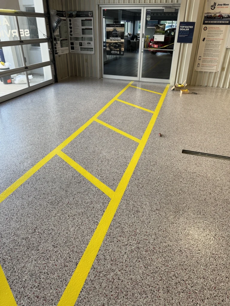 Gray industrial flooring with bright yellow safety line striping installed in a commercial building interior