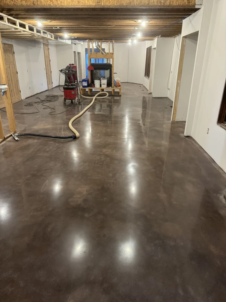 Unfinished basement with concrete floor being prepared for coating installation, showing equipment and materials