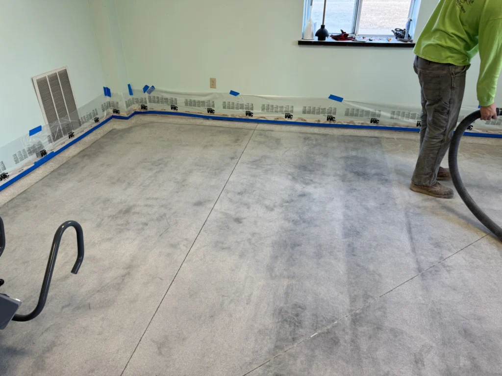 Concrete floor coating installation in progress, with blue tape sectioning off areas of the gray concrete floor.