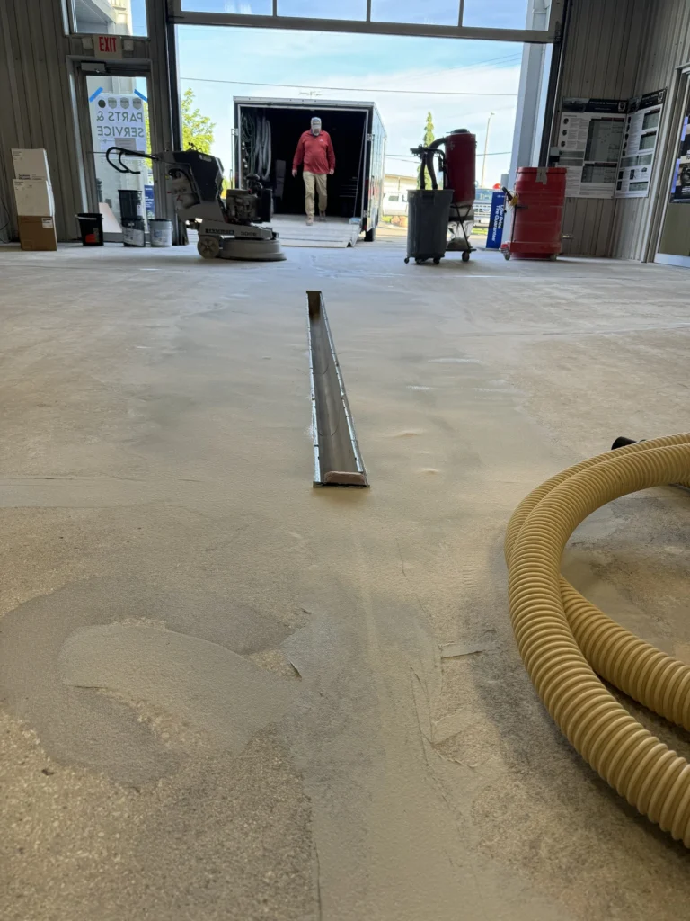 Concrete warehouse floor under repair with construction equipment and materials in the background