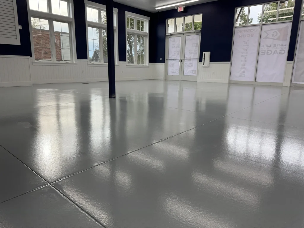 Shiny gray epoxy coated concrete floor in an empty room with windows and doors