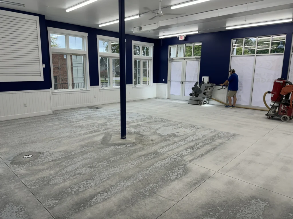 Workers installing a gray concrete floor with a textured pattern in a large commercial space with navy blue walls
