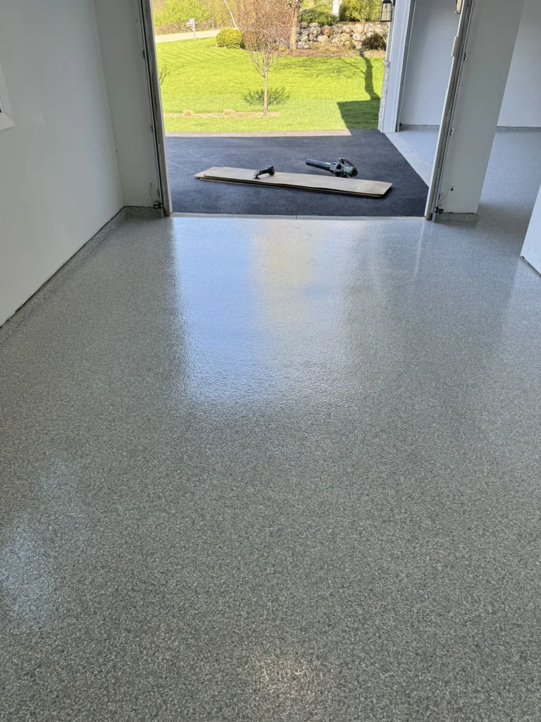 Smooth gray flake epoxy floor coating installed in a residential garage with tools on the floor