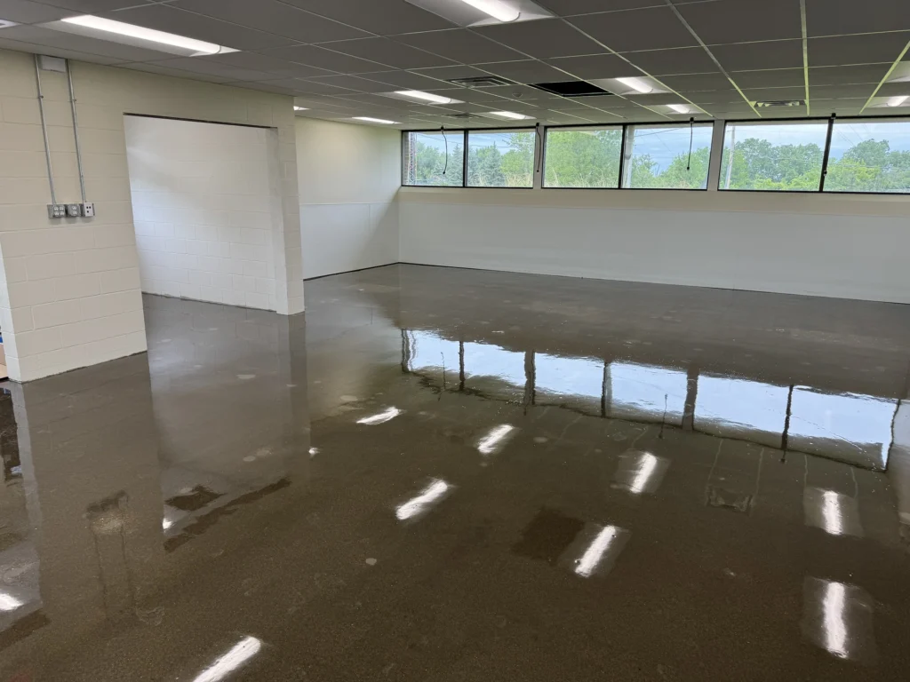 Polished concrete floor in a large office space with natural lighting and reflections on the glossy surface