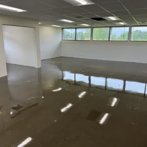 Polished concrete floor in a large office space with natural lighting and reflections on the glossy surface