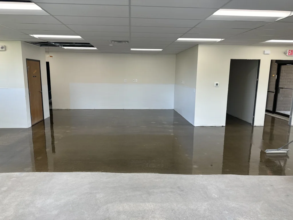 Spacious office interior with polished concrete flooring, white walls, and drop ceiling tiles