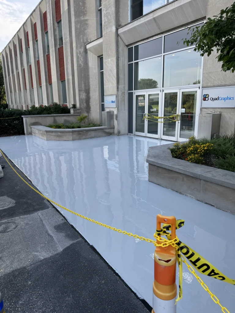 Smooth epoxy floor coating with reflections at QuadGraphics office building entrance, with caution tape and orange cones