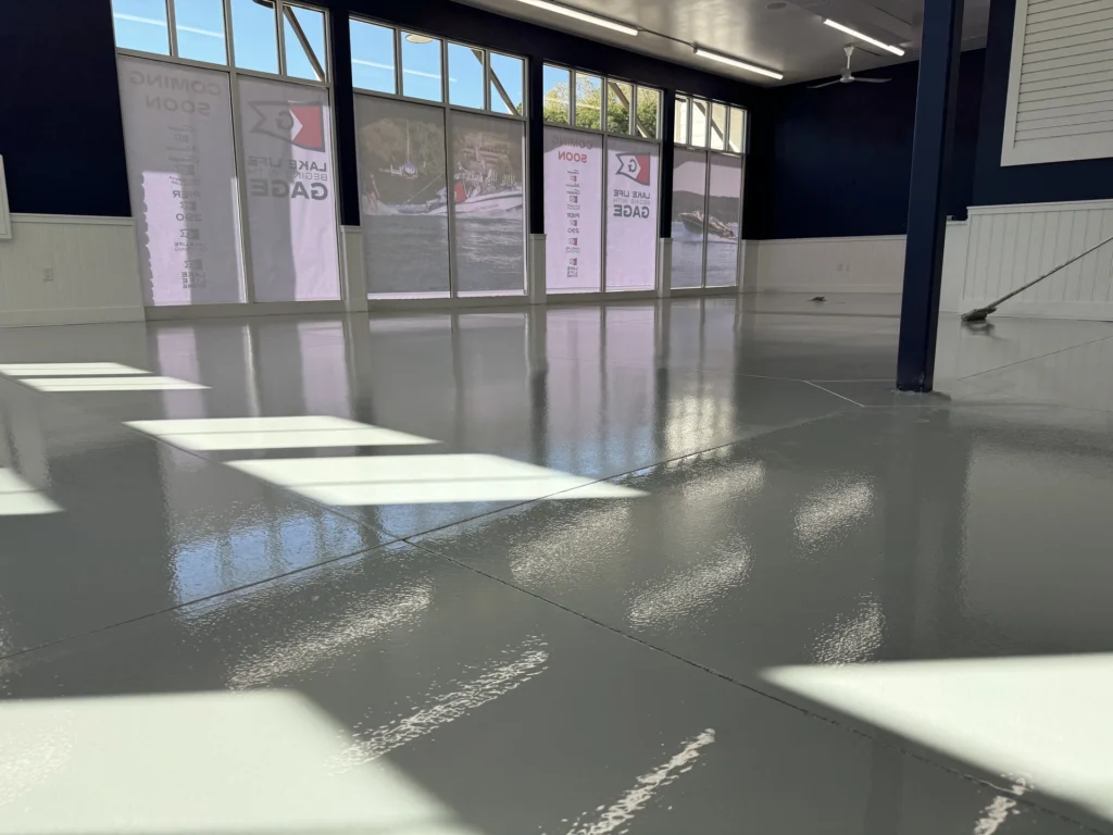 Reflective epoxy floor coating in a showroom with sunlight streaming through windows, showcasing a smooth, glossy surface