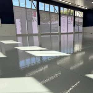 Reflective epoxy floor coating in a showroom with sunlight streaming through windows, showcasing a smooth, glossy surface